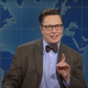 A screenshot of Elon Musk raising a finger and wearing black glasses on Saturday Night Live.